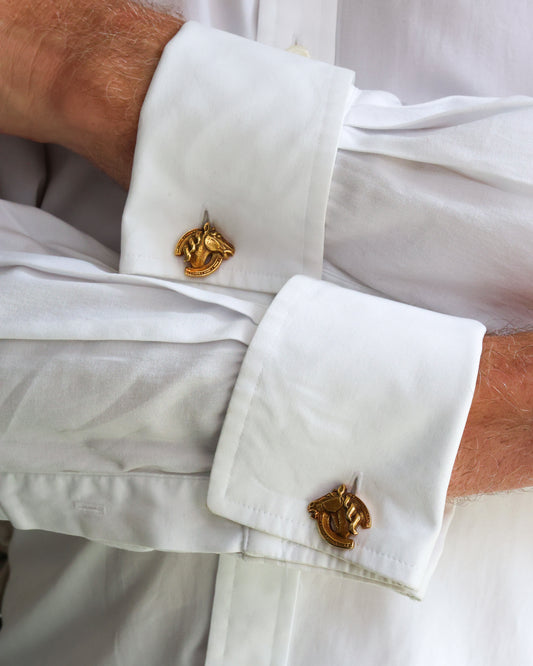 A pair of horse's head and horseshoe cufflinks in yellow gold, modelled in white shirt cuffs