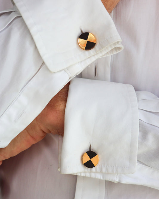 A pair of yellow gold and dark wood circular cufflinks, modelled in white shirt cuffs