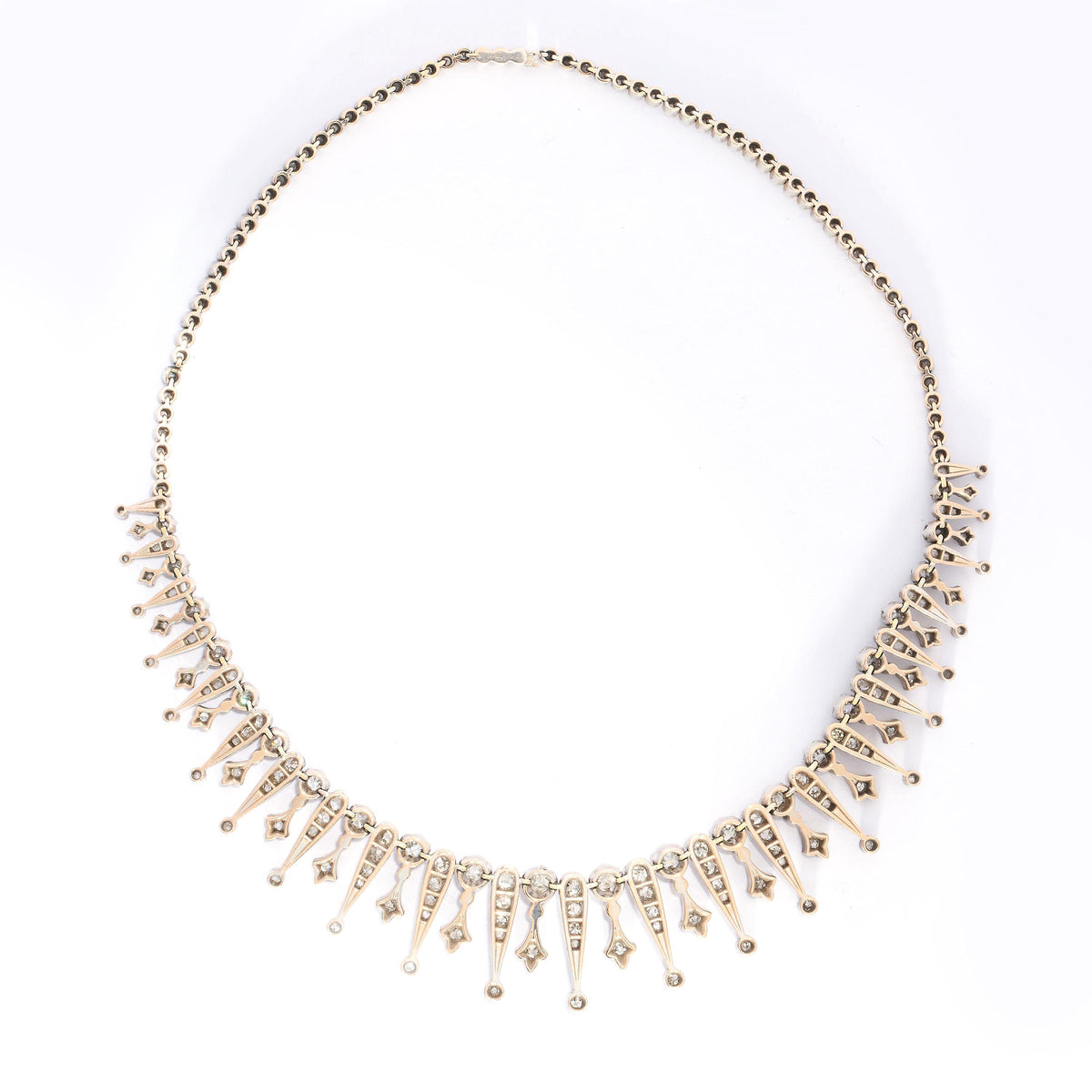 A French, antique, diamond drop necklace, featuring a graduating, old mine-cut diamond set fringe, of alternating, claw set diamond topped, grain set trefoils and reverse teardrops, with round, old mine-cut diamonds below, in pinched, trefoil settings, onto a backchain set with rose-cut diamonds, in pinched, trefoil settings, mounted in silver-upon-gold, with two boars' heads marks for silver, with a sideways fitting, box and tongue clasp