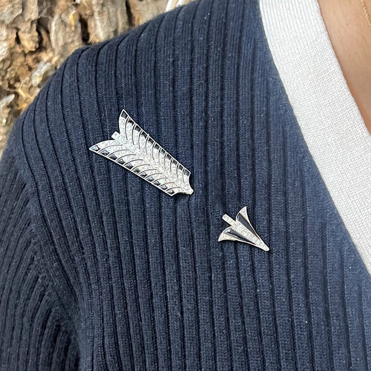 A black onyx and diamond ornate arrow jabot pin brooch, in platinum, modelled on a blue sweater