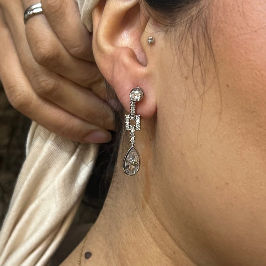 An old cut and pear cut diamond drop earring in platinum, modelled in an ear