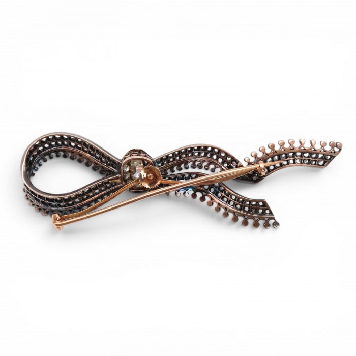An ornate bow brooch set with diamonds, in silver and yellow gold