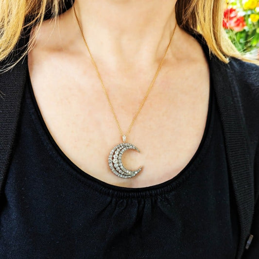 A diamond set crescent moon pendant in silver and yellow gold, with a gold chain, modelled