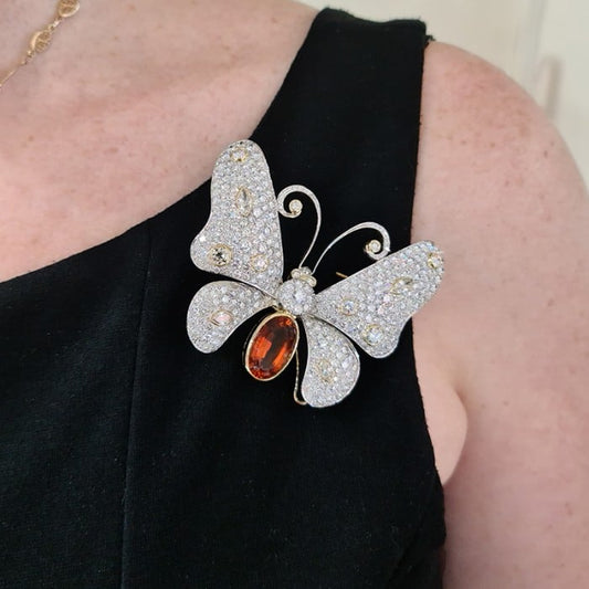 A large butterfly brooch with a citrine body, diamond set wings, eyes and antennae, in platinum and yellow gold, modelled on a black dress
