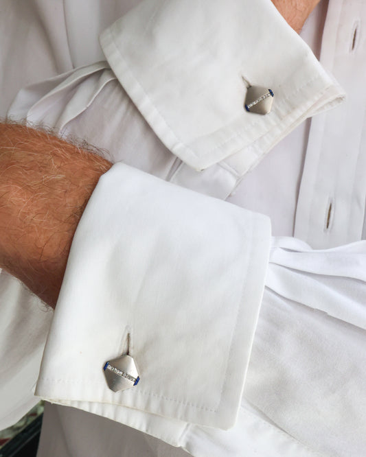 A pair of cut-cornered square cufflinks in platinum, with sapphires and diamonds, modelled in a white shirt