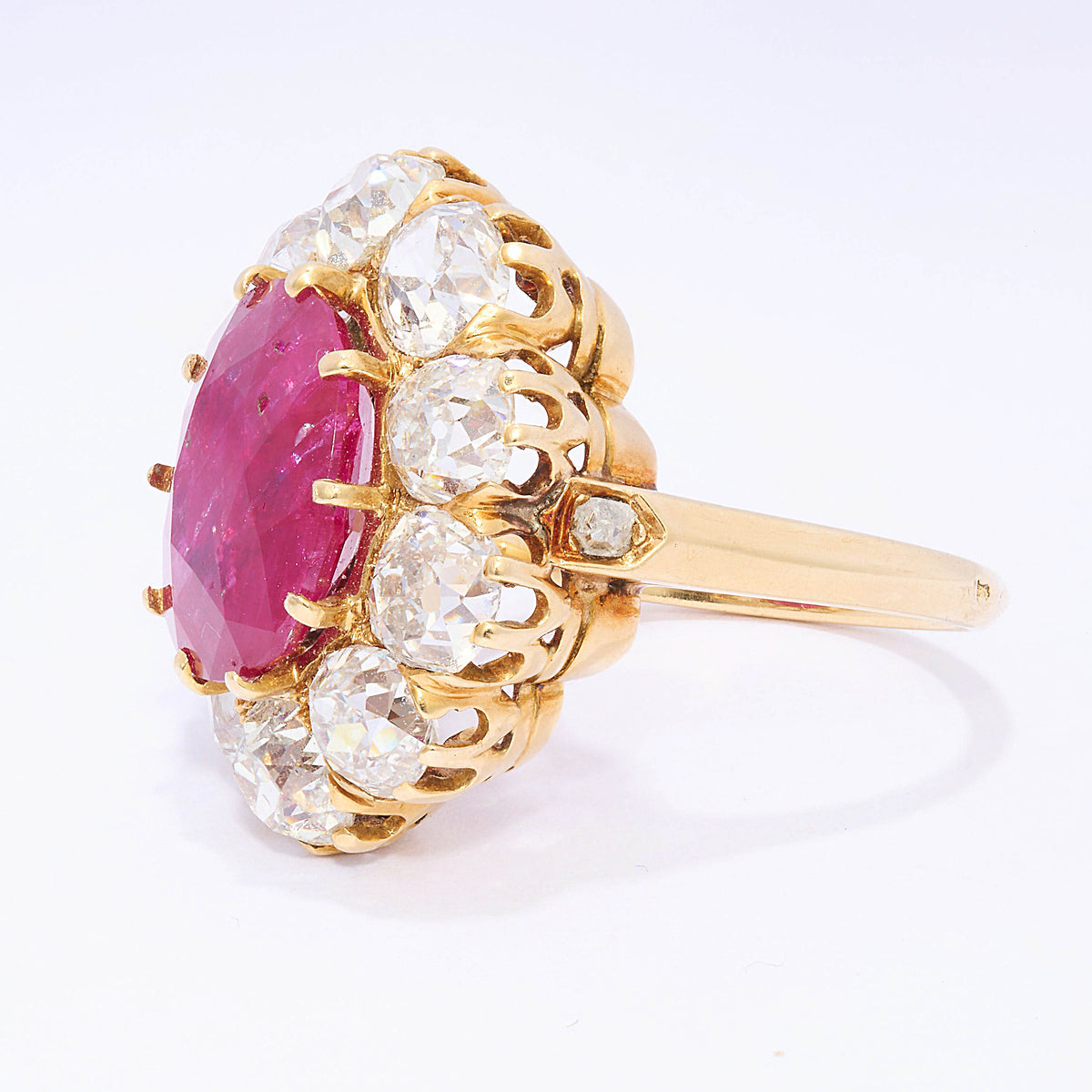A French antique cushion-cut ruby and diamond oval-shaped cluster ring, with ten, old-cut diamonds in claw settings, mounted in yellow gold, with a French eagle head mark, for 18ct gold, circa 1890.