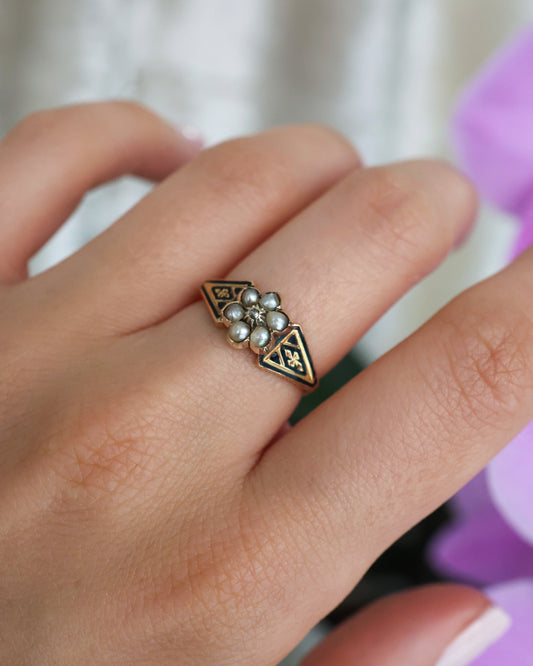 A pearl and diamond flower cluster ring with black enamel shoulders in yellow gold, modelled on a hand