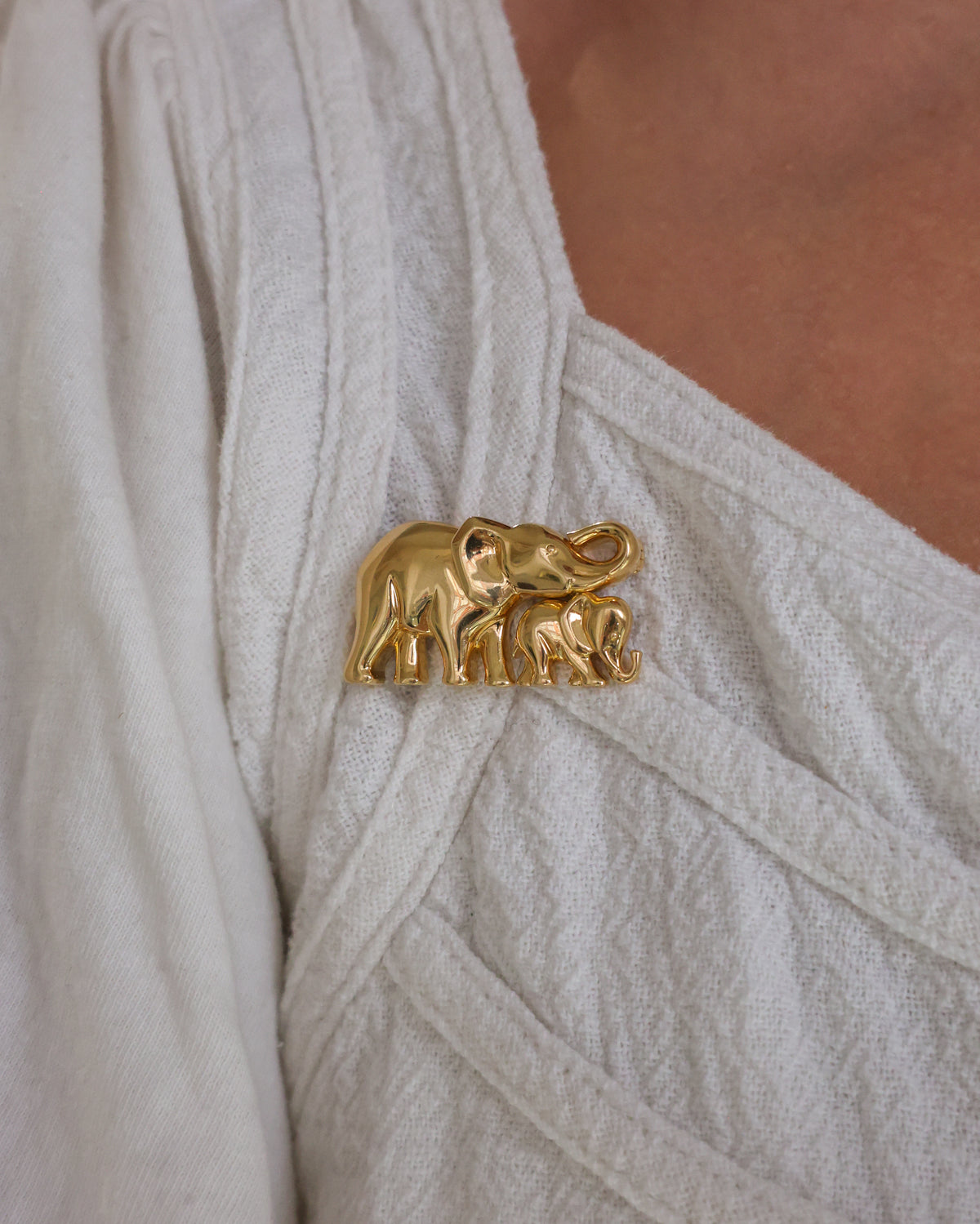 A vintage Cartier 18ct yellow gold, mother and calf elephant brooch, featuring two stylised, geometric, dome shaped elephants, with the calf closely coupled to the mother, on a shepherd's hook. The can be worn as a separate pendant, signed Cartier.