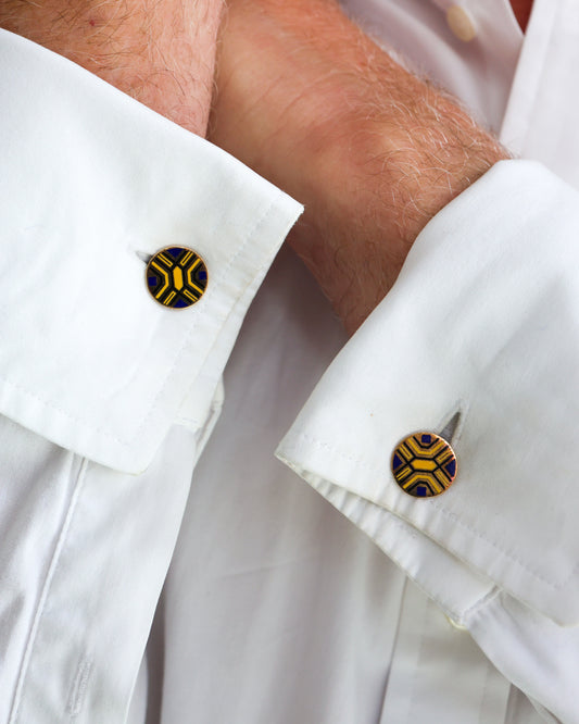A pair of circular yellow gold cufflinks with yellow and blue enamel, modelled in white shirt cuffs