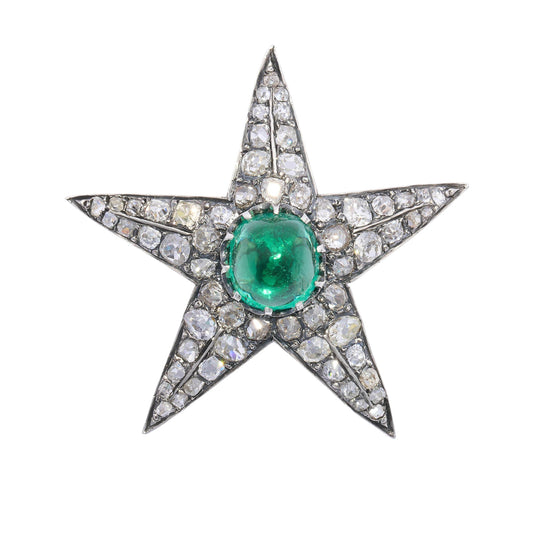 A star shaped brooch in silver and gold, with a cabochon emerald centre surrounded by old cut diamonds