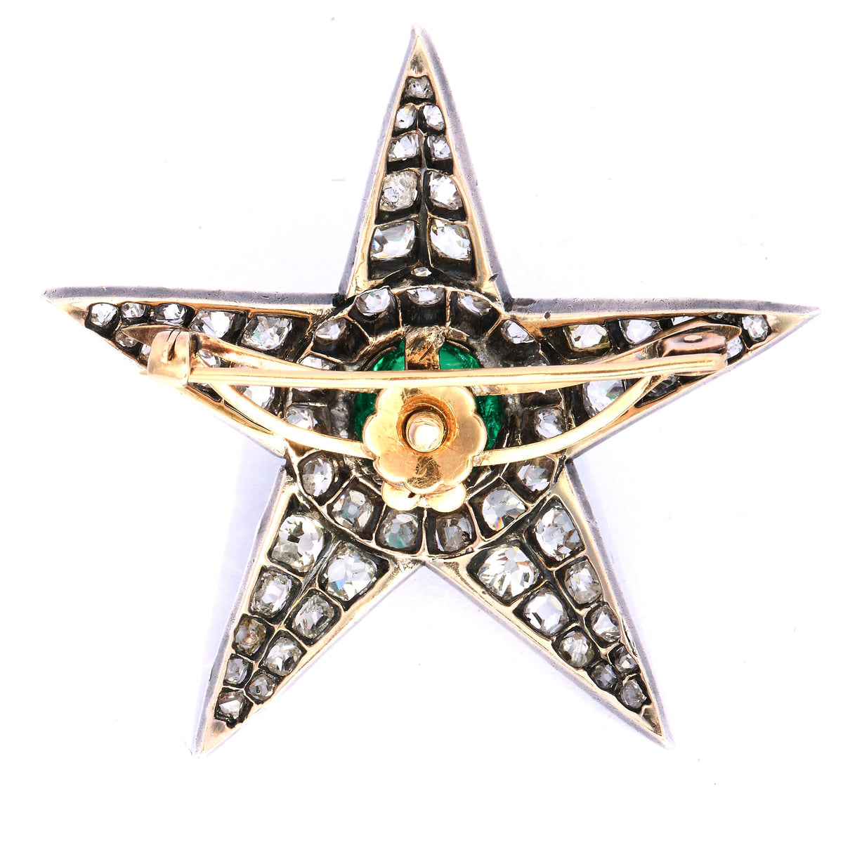 A star shaped brooch in silver and gold, with a cabochon emerald centre surrounded by old cut diamonds