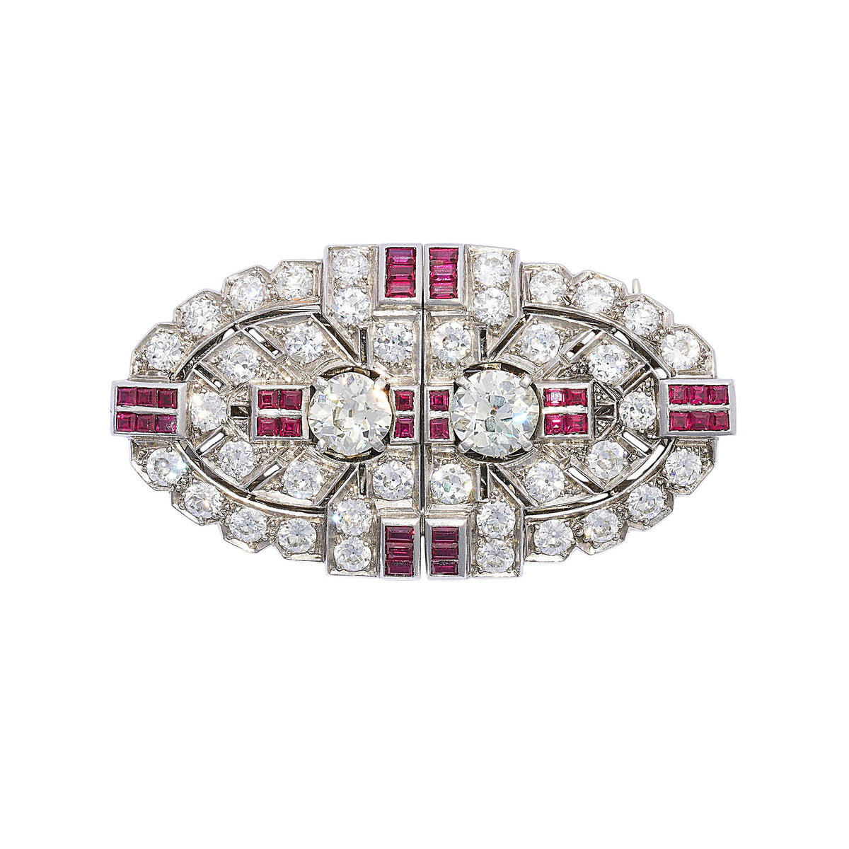 An Art Deco diamond and ruby double clip brooch, in an oval, geometric design, which can be worn as a single brooch or as a pair of dress clips on the neckline or collar of a dress. The design features two European old-cut diamonds, in four claw settings, alternating with groups of four calibré-cut rubies, in channel settings, with further, similarly set groups of six rubies, at the quarters; with an old-cut diamond, grain set, open work, plaque design, resembling arrow fletching, surrounding the centre pai