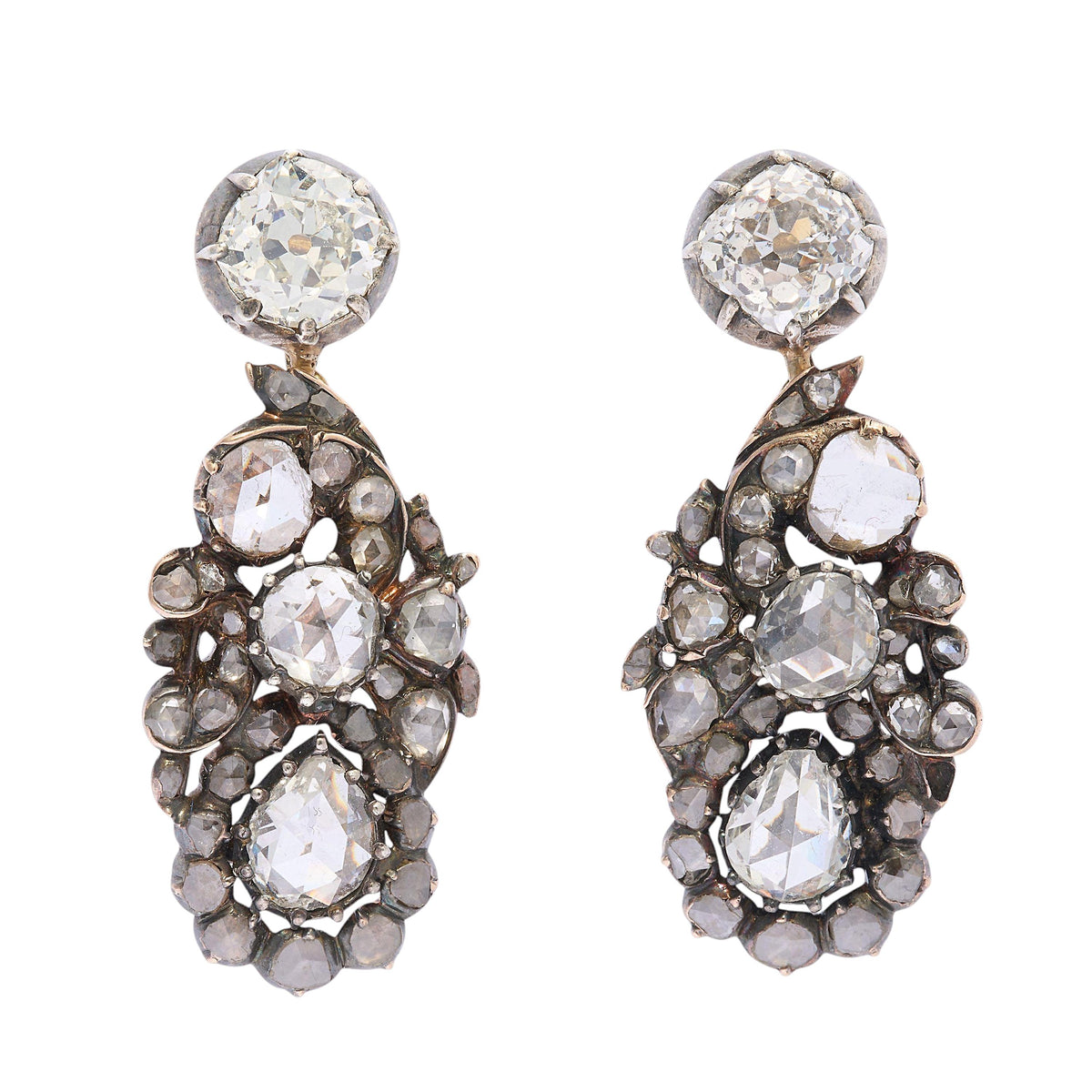 A pair of diamond, silver and gold cluster drop earrings, with stud tops, with old-cut diamonds, in cut down settings, with fancy cluster drops, set with three larger rose-cut diamond, the bottom diamonds are&nbsp; pear shaped, with surrounding, smaller rose-cut diamonds, in a scrolling foliate design, in cut down settings, mounted in silver-upon-gold, circa 1880.