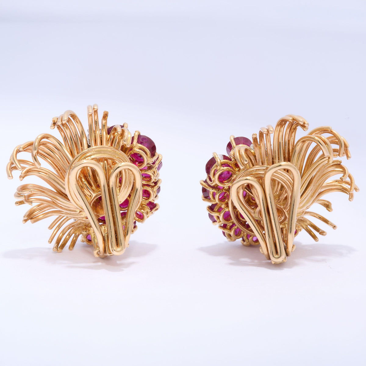 A pair of round ruby and round diamond floral spray earrings in yellow gold