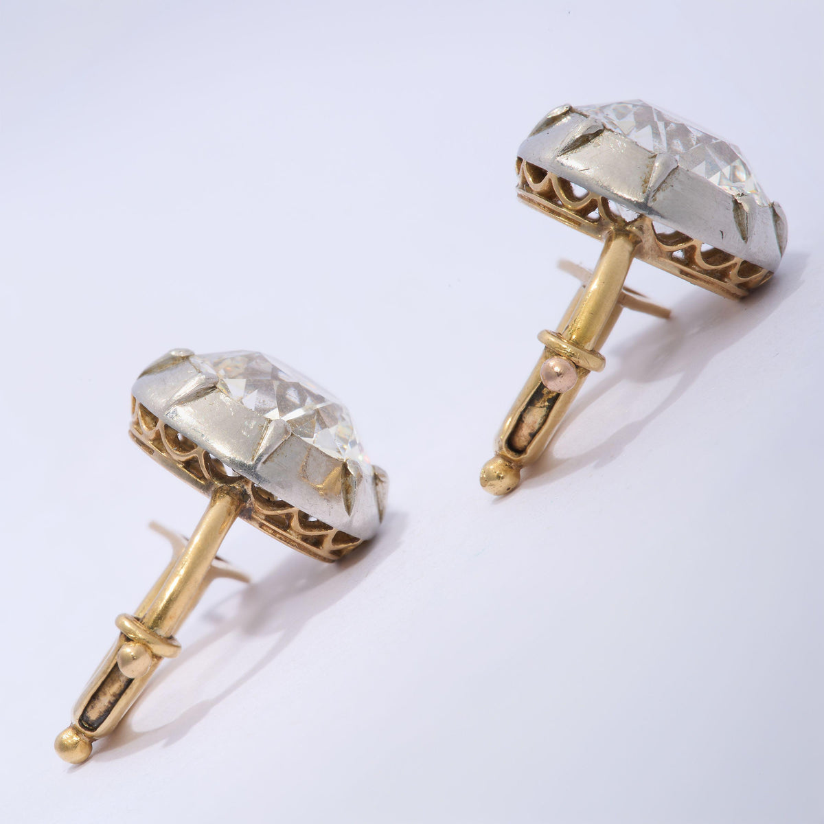 A pair of old cut diamond single stone earrings in silver, with yellow gold hinged clip on fittings