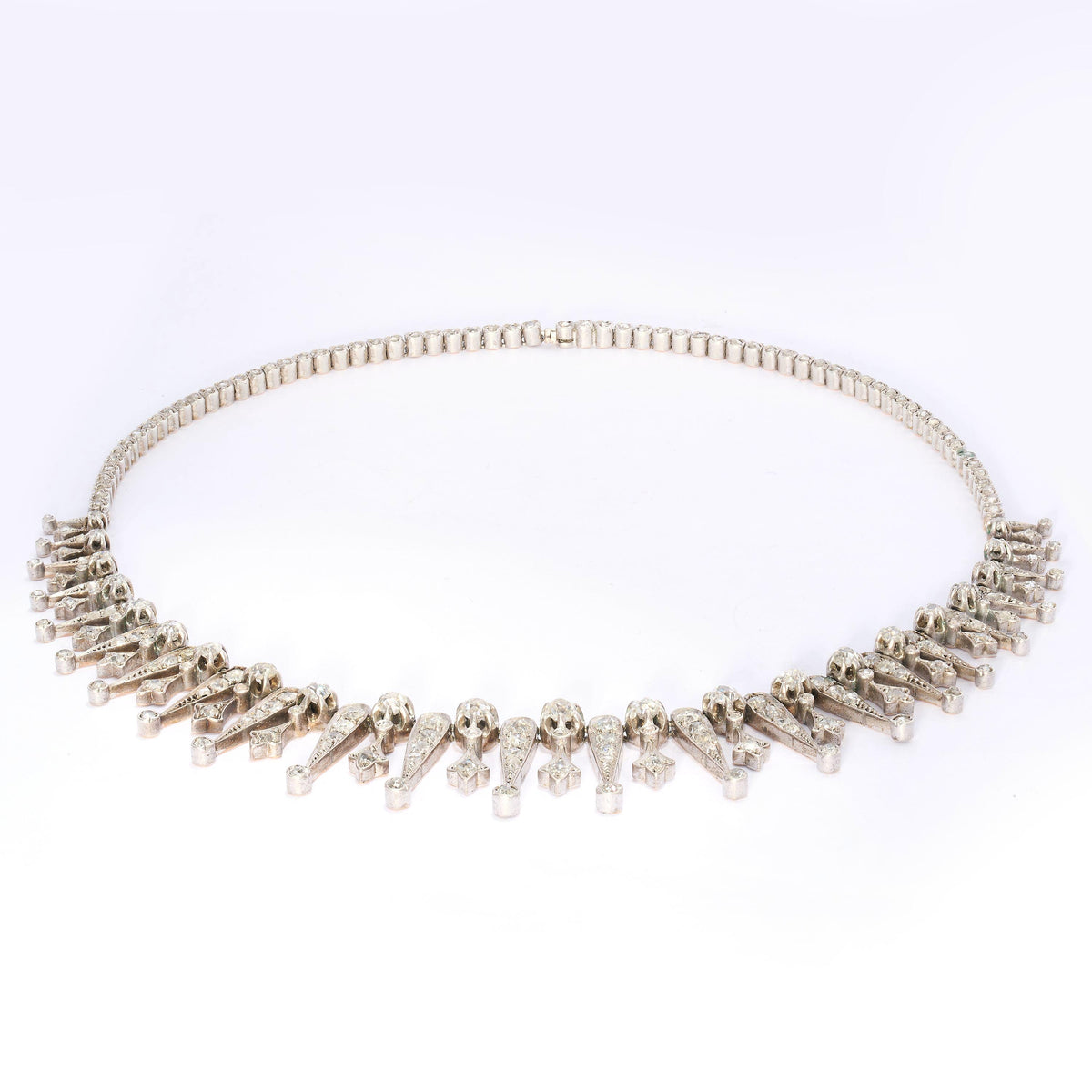 A French, antique, diamond drop necklace, featuring a graduating, old mine-cut diamond set fringe, of alternating, claw set diamond topped, grain set trefoils and reverse teardrops, with round, old mine-cut diamonds below, in pinched, trefoil settings, onto a backchain set with rose-cut diamonds, in pinched, trefoil settings, mounted in silver-upon-gold, with two boars' heads marks for silver, with a sideways fitting, box and tongue clasp