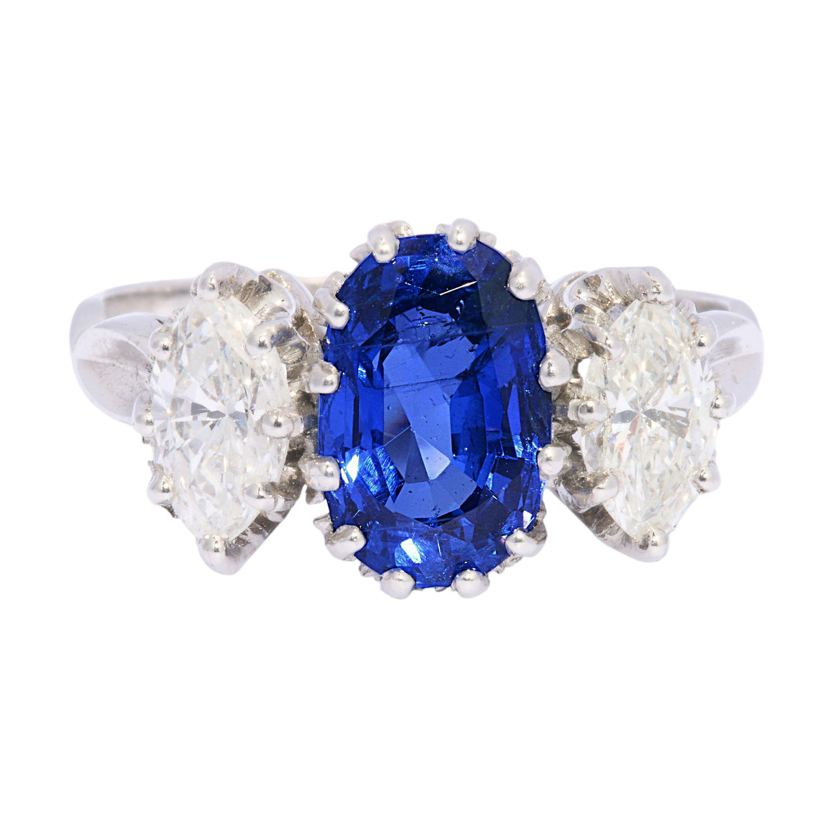 An oval sapphire and marquise cut diamond three stone ring in platinum