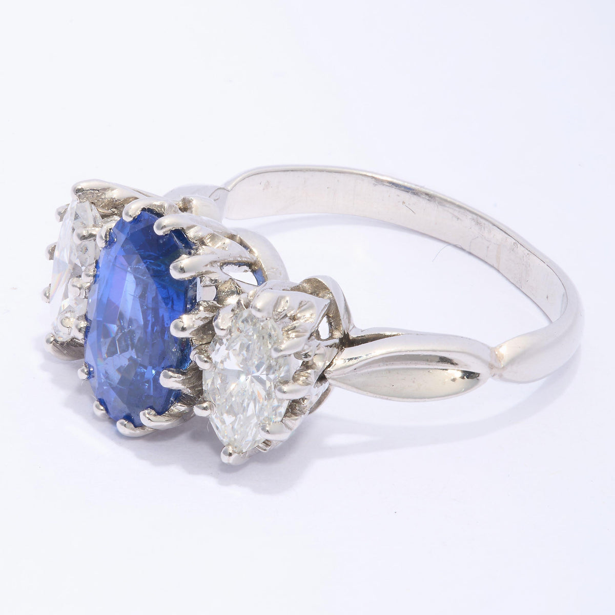 An oval sapphire and marquise cut diamond three stone ring in platinum