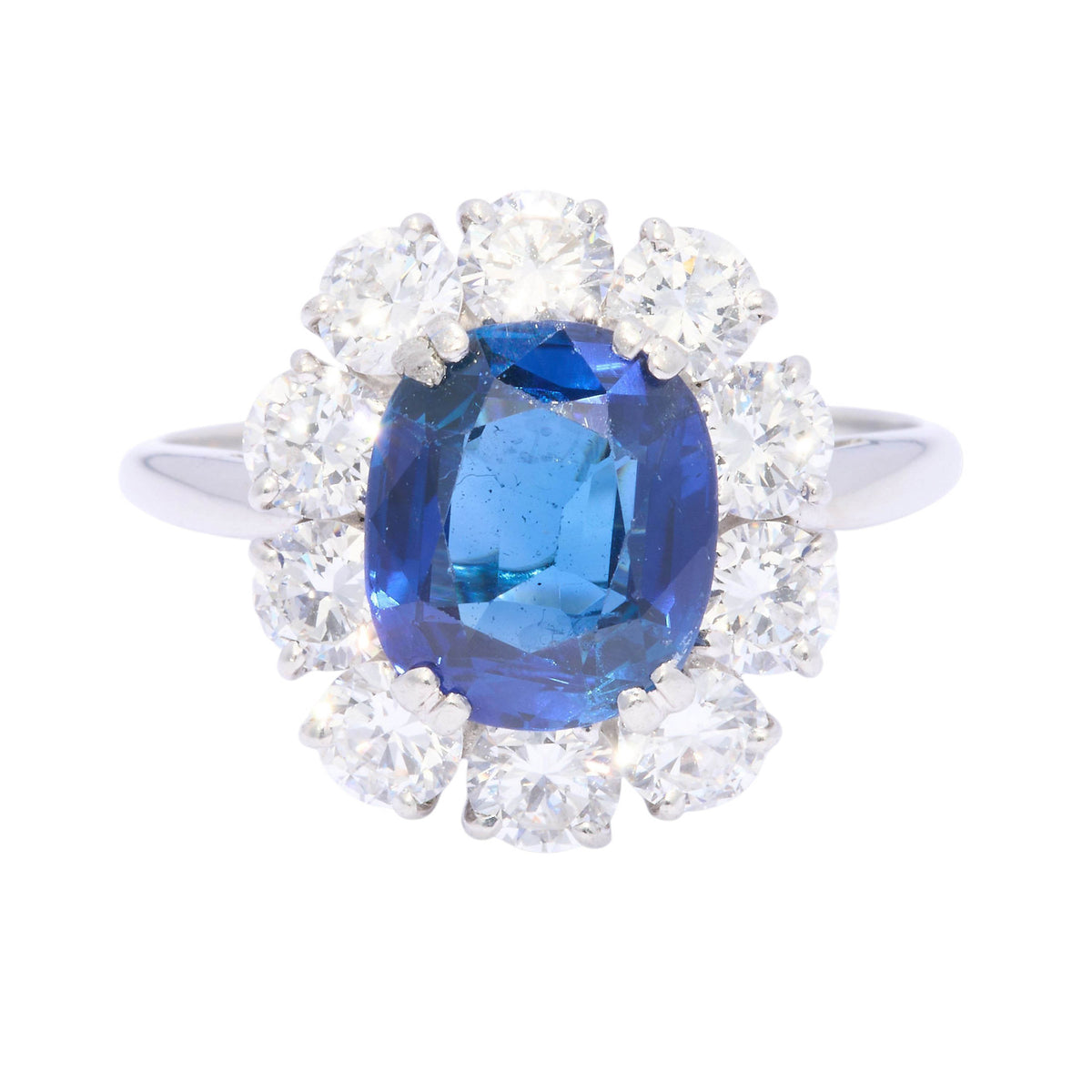 An oval sapphire and round diamond claw set cluster ring in platinum
