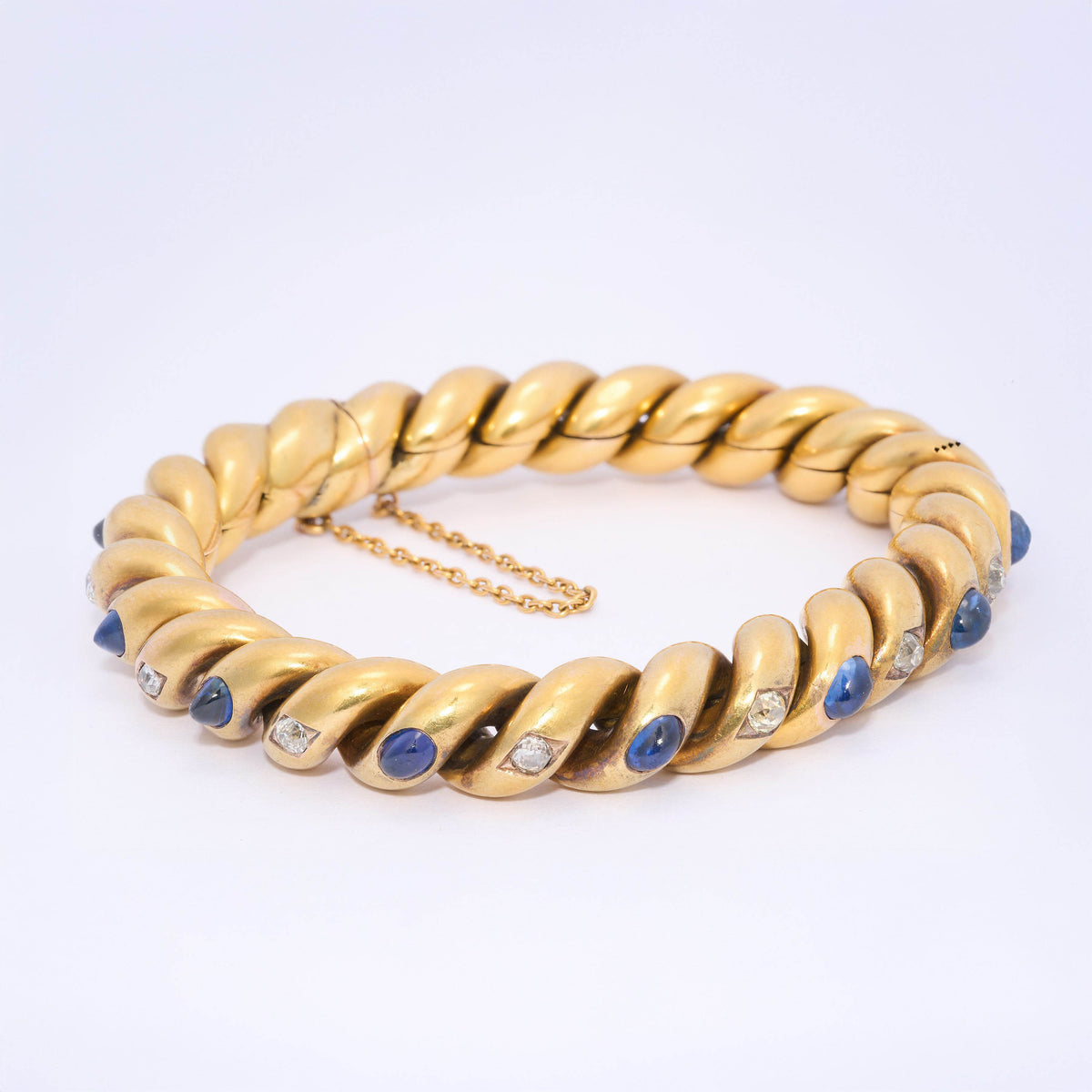 A yellow gold twisted bracelet set with cabochon sapphires and old cut diamonds