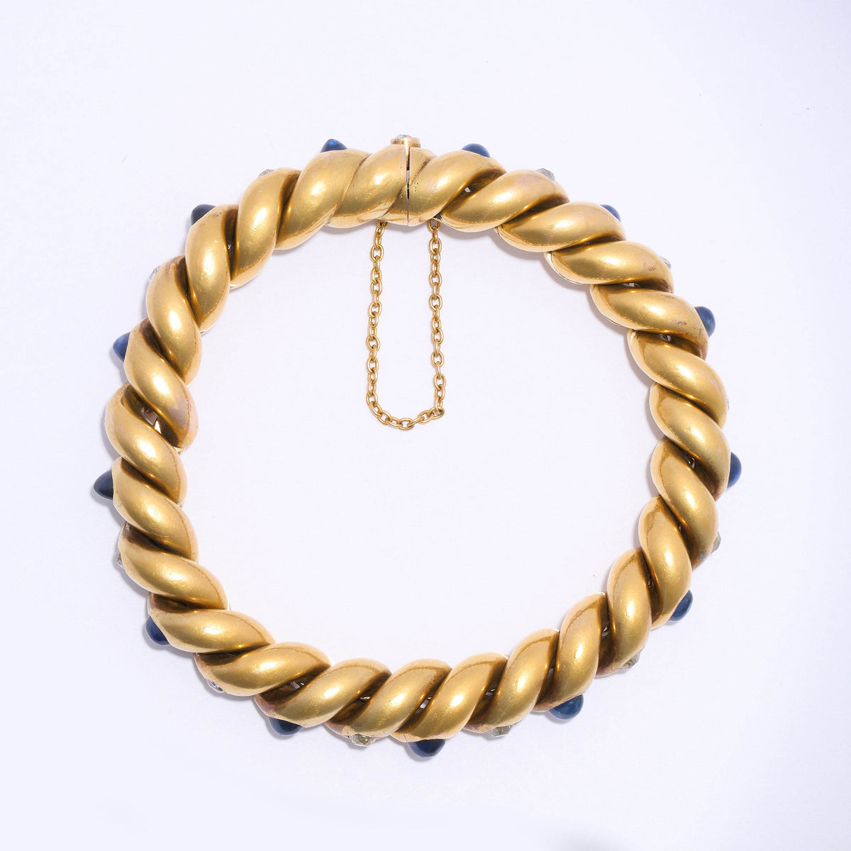 A yellow gold twisted bracelet set with cabochon sapphires and old cut diamonds