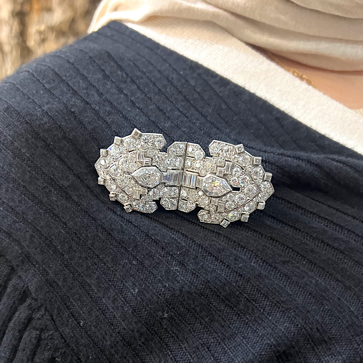 A diamond double clip brooch in platinum and white gold, modelled on a blue sweater