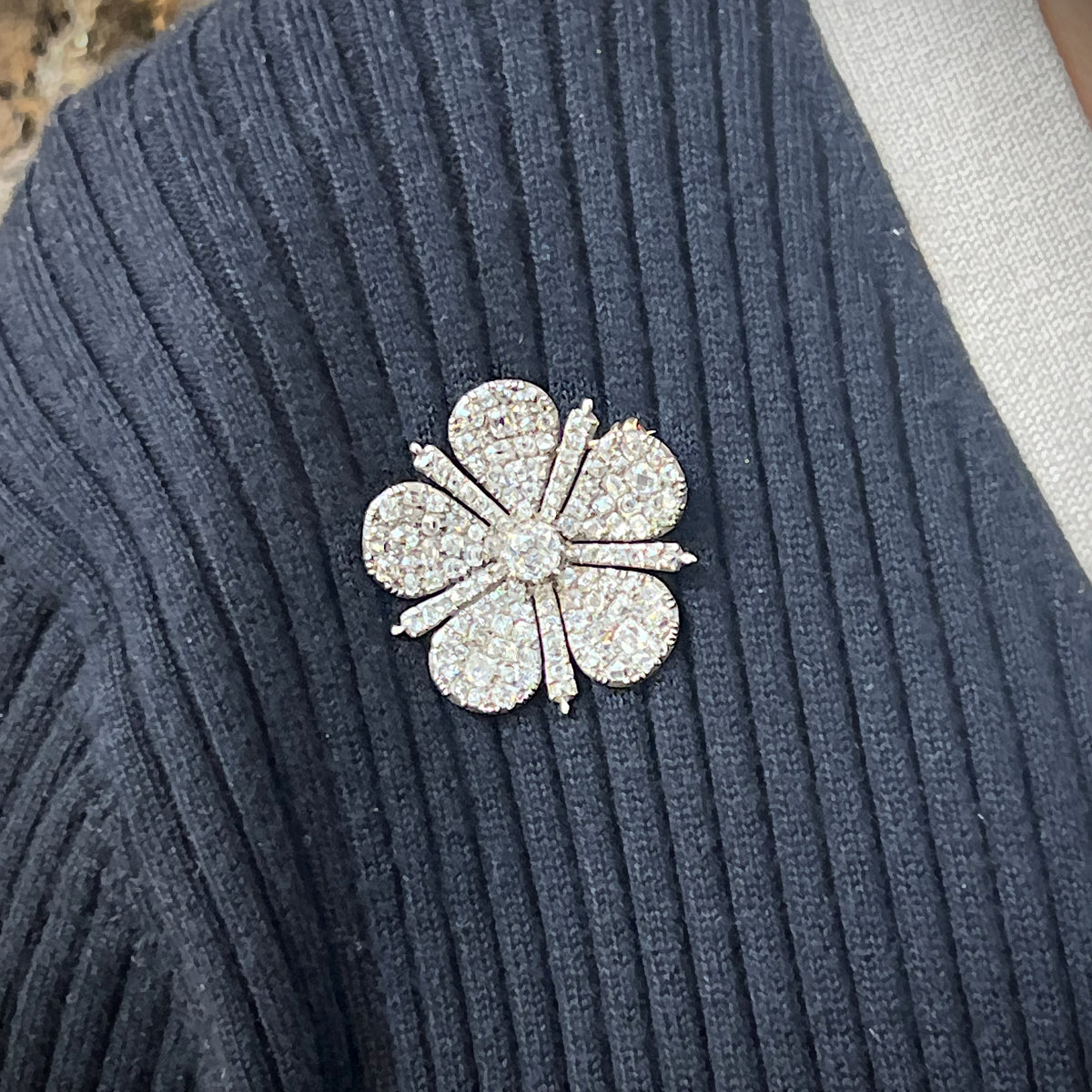An antique old cut diamond flower brooch in silver and gold, modelled on a blue sweater