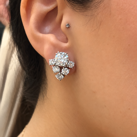 A round diamond V-shaped cluster earring in platinum, modelled in an ear