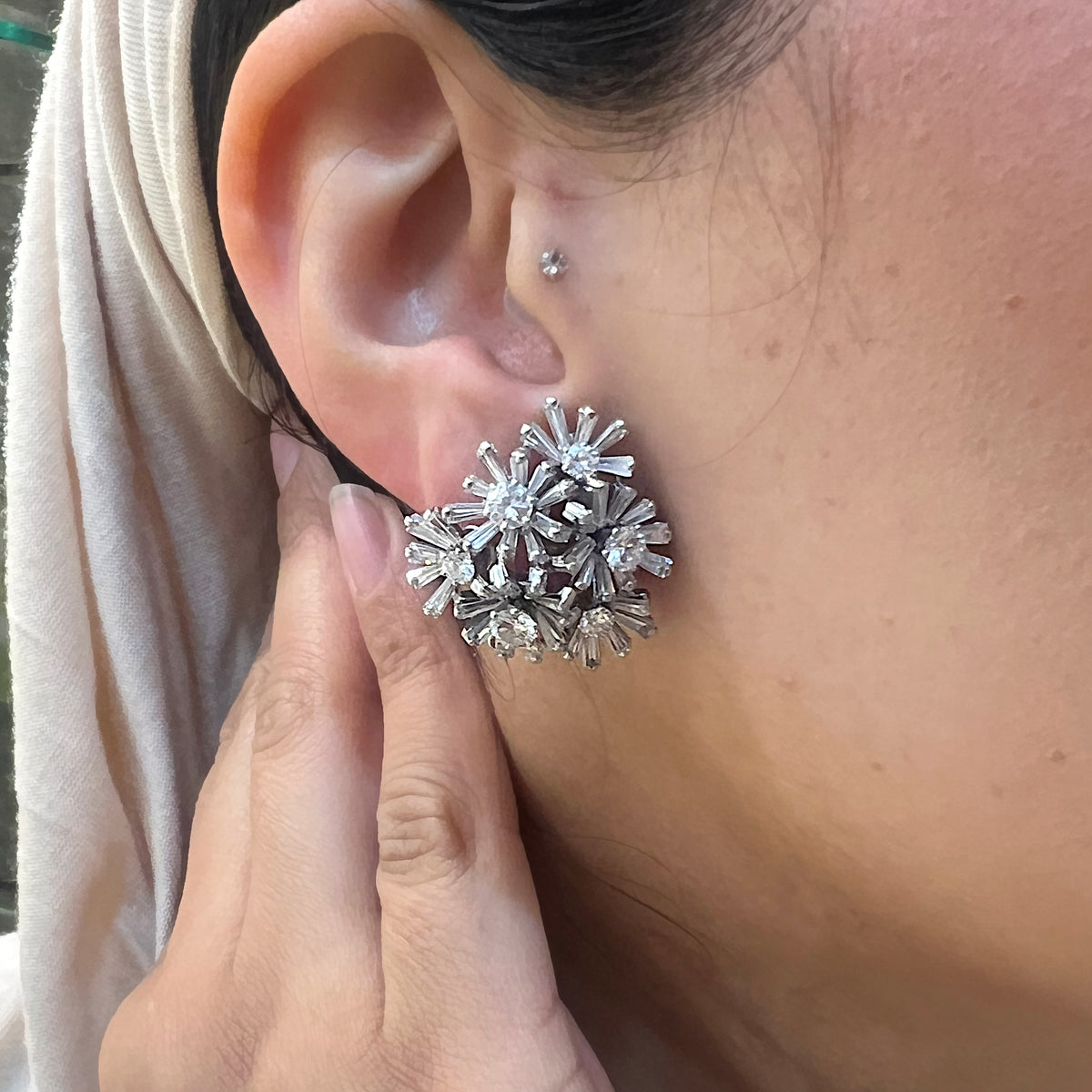A vintage multi floral cluster earring set with diamonds, in white gold, modelled in an ear