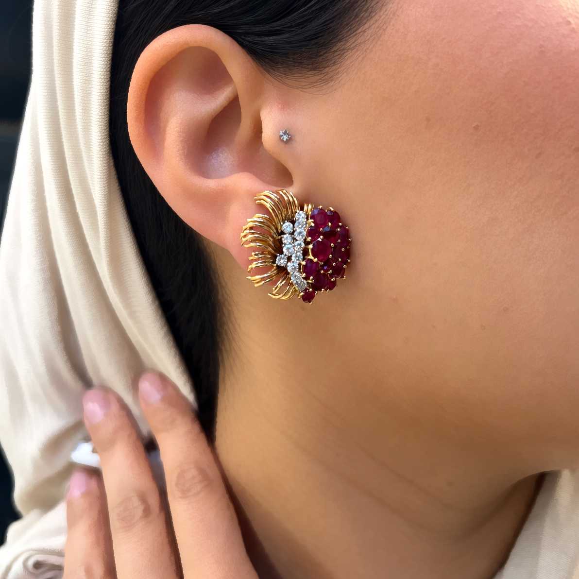 A round ruby and round diamond floral spray earring in yellow gold, modelled in an ear