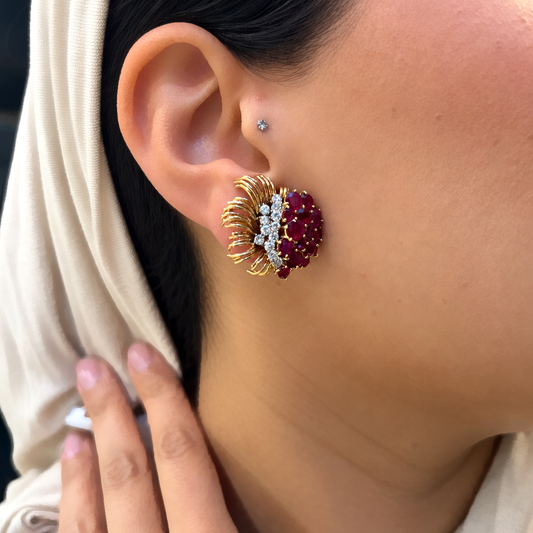 A round ruby and round diamond floral spray earring in yellow gold, modelled in an ear