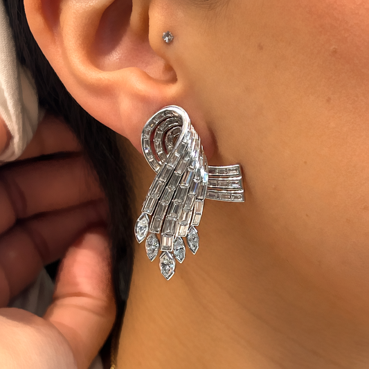 An Art Deco design baguette cut and marquise cut diamond cocktail earring in platinum, modelled in an ear