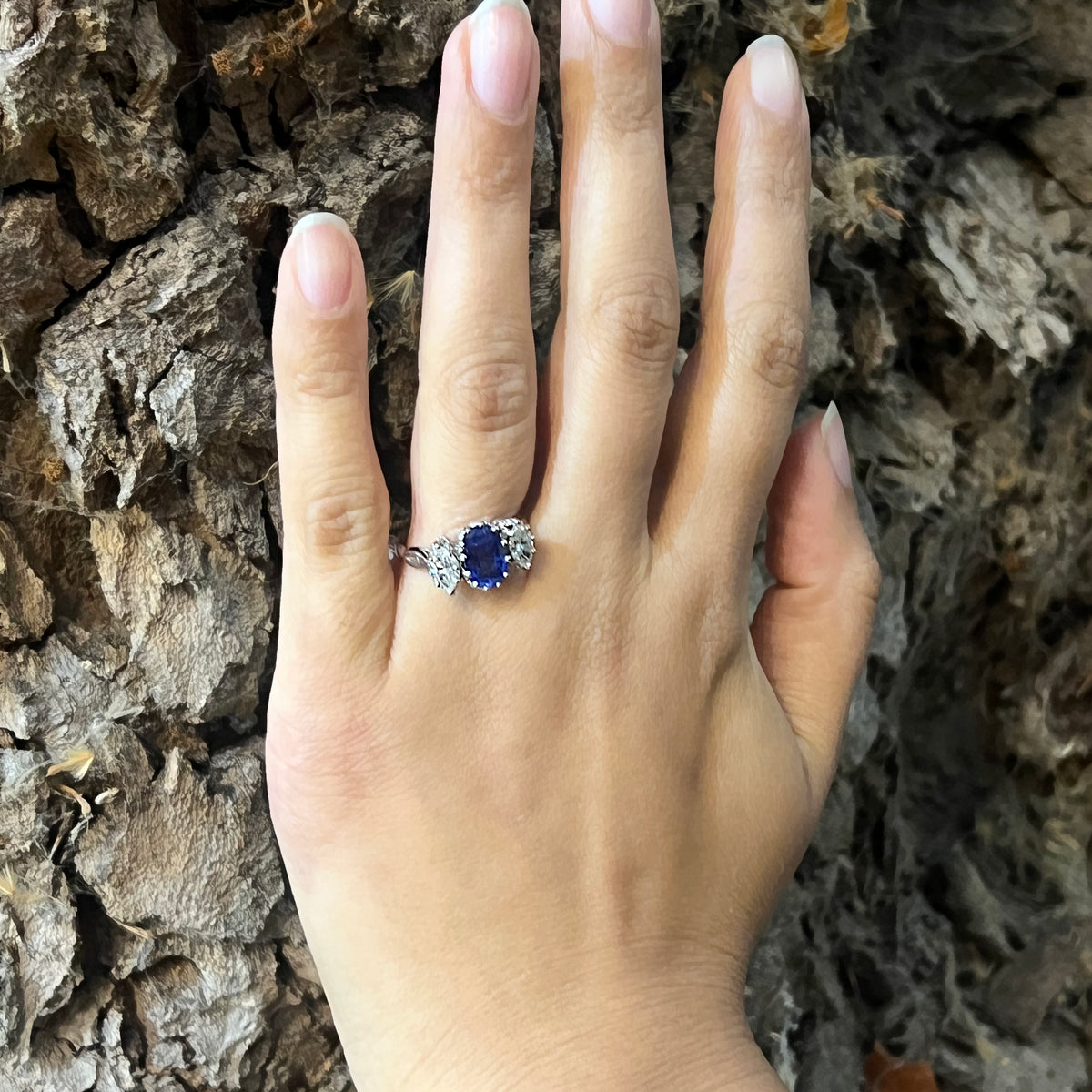 An oval sapphire and marquise cut diamond three stone ring in platinum, modelled on a hand