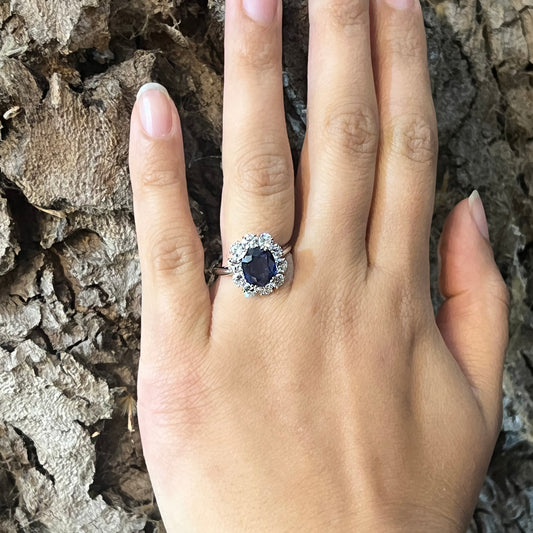 An oval sapphire and round diamond claw set cluster ring in platinum, modelled on a hand