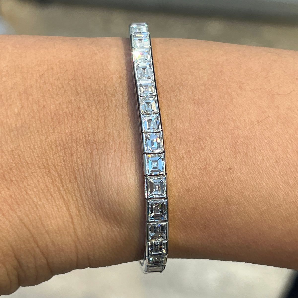 A square cut diamond channel set line bracelet in platinum, modelled on a wrist