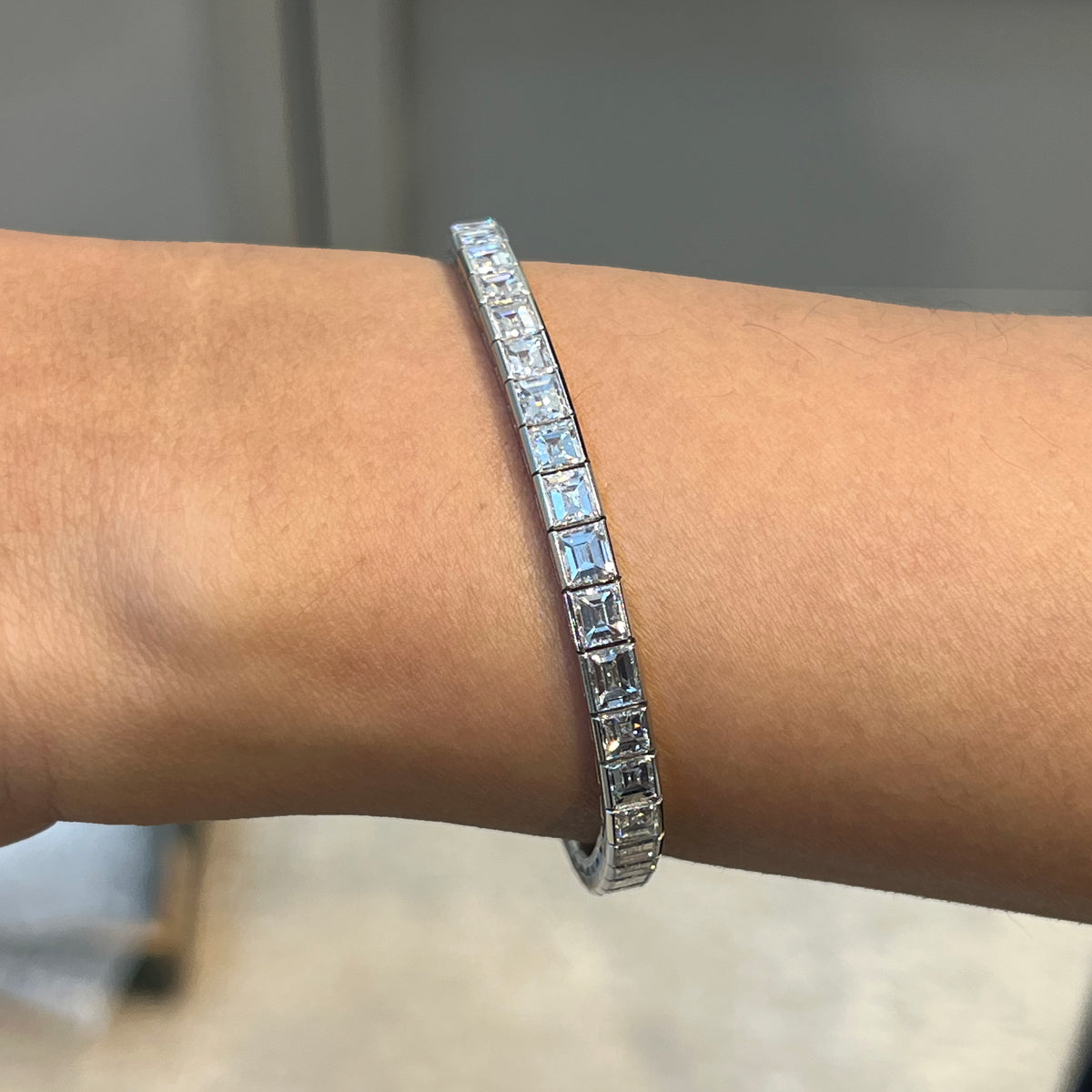 A square cut diamond channel set line bracelet in platinum, modelled on a wrist