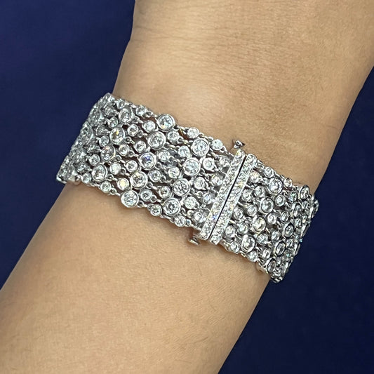 A wide multi-row bracelet set with brilliant cut diamonds in white gold, modelled on a wrist