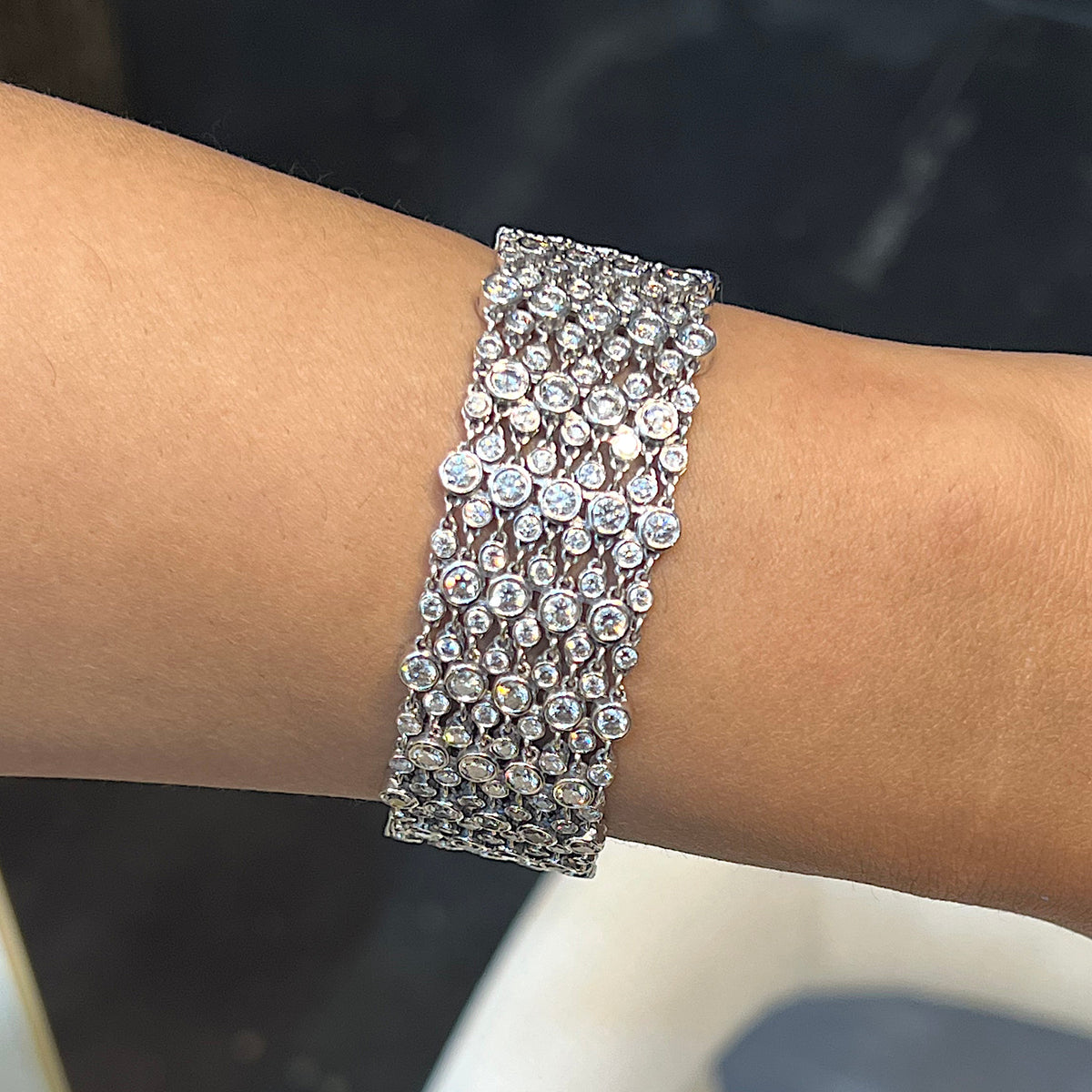A wide multi-row bracelet set with brilliant cut diamonds in white gold, modelled on a wrist
