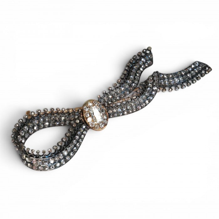 An ornate bow brooch set with diamonds, in silver and yellow gold