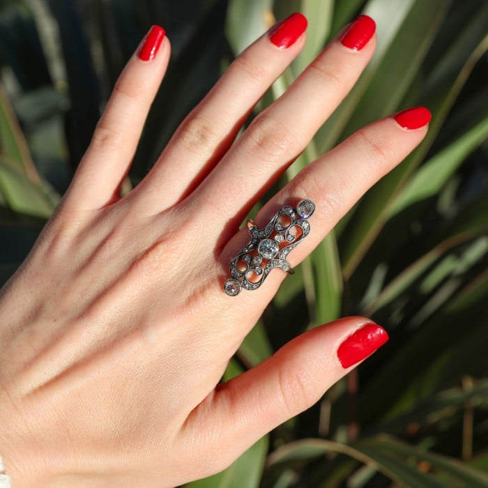 An openwork, decorative antique ring set with diamonds, in gold and silver, modelled on a hand
