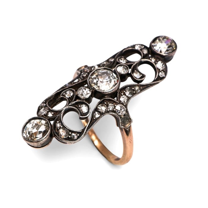 An openwork, decorative antique ring set with diamonds, in gold and silver
