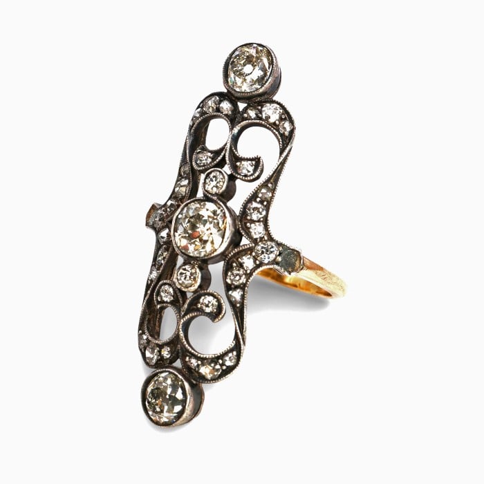 An openwork, decorative antique ring set with diamonds, in gold and silver