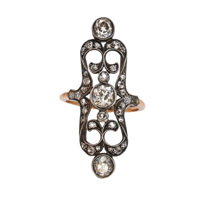 An openwork, decorative antique ring set with diamonds, in gold and silver