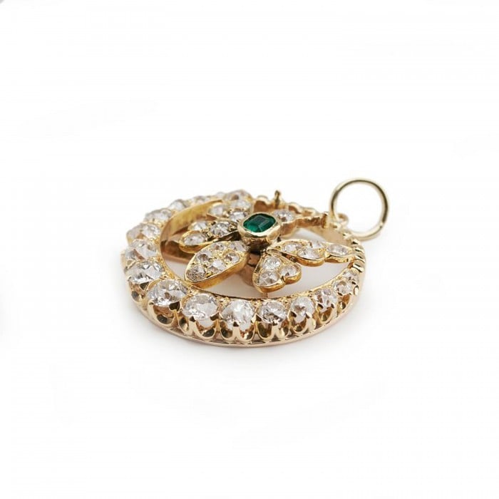 A butterfly open circle pendant set with an emerald and diamonds, in yellow gold