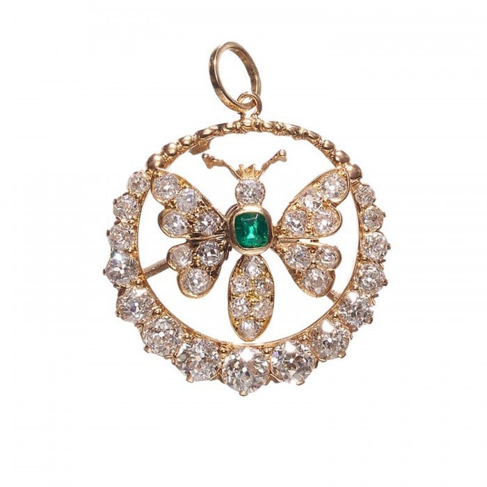 A butterfly open circle pendant set with an emerald and diamonds, in yellow gold