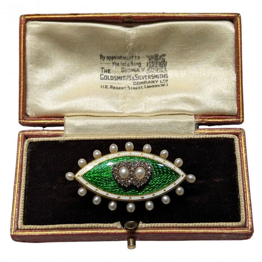 A navette shaped brooch set with pearls and diamonds, with a green and white enamel background, in gold and silver, in an antique box