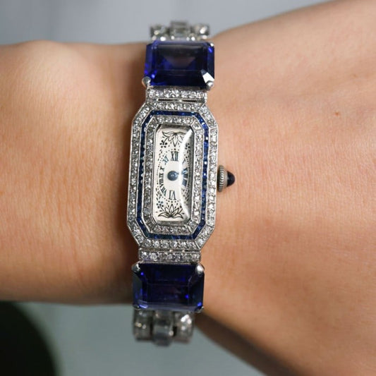 An antique cocktail watch set with blue stones and diamonds, in platinum, modelled on a wrist