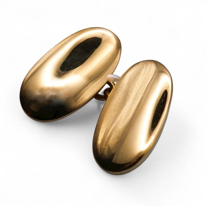 An oval plain yellow gold cufflink