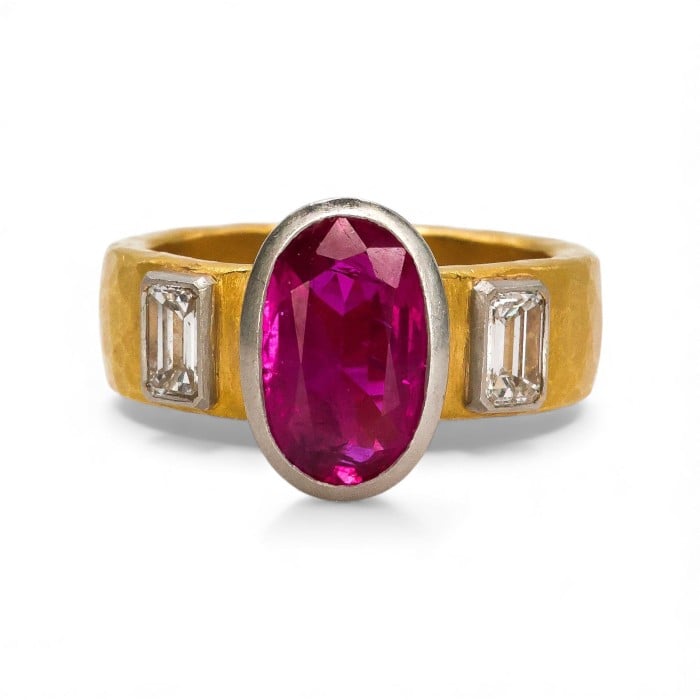 A yellow gold and platinum band ring with an oval ruby centre and emerald cut diamond shoulders