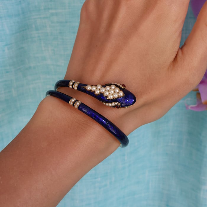 A snake bangle bracelet with pearls, ruby eyes and blue enamel, in yellow gold, modelled on a wrist